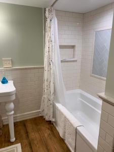 Baño blanco con bañera y lavamanos en Innkeeper's Place B&B, en Stafford Springs