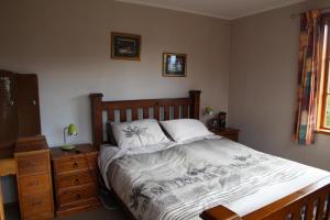 a bedroom with a bed with a wooden headboard and a dresser at Batch with a View in Te Anau