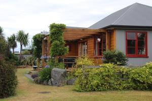 a wooden house with a red window and a yard at Batch with a View in Te Anau