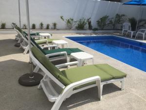 a row of chaise lounge chairs next to a pool at DEPARTAMENTOS LALO in Zihuatanejo