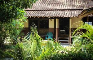 a house with two blue chairs in a garden at Harrys Oceanhouse 2 Pacitan in Pacitan