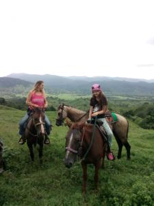 dos chicas montando a caballo en un campo en Hostel Wunderbar, en Puerto Lindo