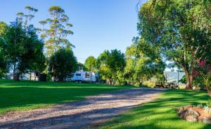 an rv parked in a field with trees and a road at Dorrigo Mountain Holiday Park in Dorrigo