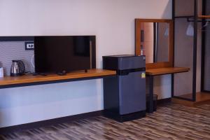 a room with a desk with a tv and a refrigerator at S.S.Hotel Nangrong in Nang Rong