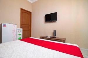 um quarto com uma cama e uma televisão na parede em RedDoorz Syariah near Mercu Buana University em Jakarta