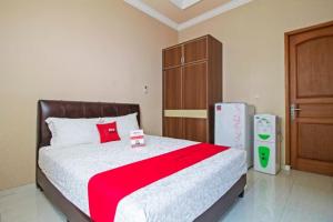um quarto com uma cama e um frigorífico em RedDoorz Syariah near Mercu Buana University em Jakarta