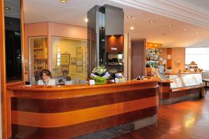 a woman sitting at a bar in a restaurant at Hotel Frate Sole in Assisi