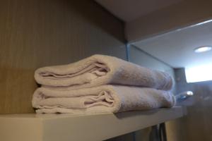 a pile of towels sitting on a shelf in a bathroom at Wirton Seminyak in Denpasar