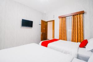 a bedroom with two beds and a television in it at RedDoorz near Taman Rekreasi Selecta in Malang