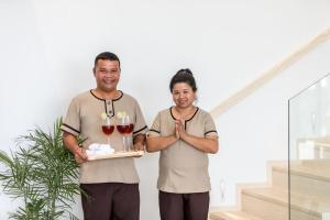 a man and a woman holding a tray of wine glasses at KW VILLA in Ban Bang Po