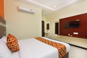 a hotel room with a bed and a flat screen tv at Hotel Ramcharan Residency, Tirupati in Tirupati