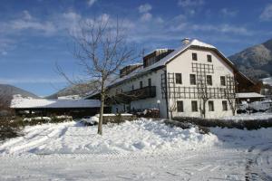 Un bâtiment blanc avec un arbre dans la neige dans l'établissement Appartementhaus Lechnerhof, à Brunico