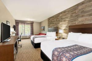 a hotel room with two beds and a flat screen tv at La Quinta Inn and Suites by Wyndham Bloomington in Bloomington