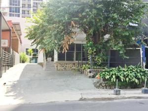 a building with a tree in front of a street at SERENADE Lodging Rooms in Panama City