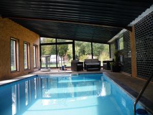 a swimming pool in a house with a large window at Gîte Lorengrain in Bruyères-et-Montbérault