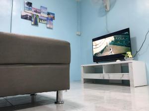 - un salon avec une télévision et un canapé dans l'établissement Blue House Hat Yai, à Hat Yai