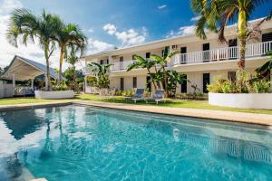 a swimming pool in front of a house with palm trees at Tropicana Lagoon Apartments in Port Vila