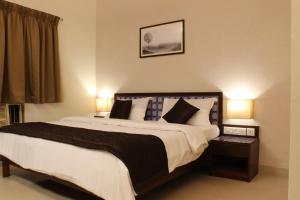 a bedroom with a large bed with two lamps at Ria Residency in Panaji