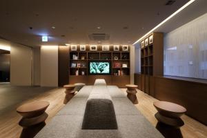 um átrio com bancos e uma televisão num edifício em Keio Presso Inn Tokyo Station Yaesu em Tóquio