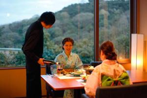 un hombre y una mujer sentados en una mesa comiendo comida en Kotohira Grand Hotel Sakuranosho en Kotohira