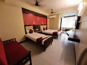 a hotel room with two beds and a couch at Ravi Krishna Inn in Puducherry
