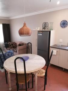 a kitchen and living room with a table and a refrigerator at Lucias Cottage in Cape Town