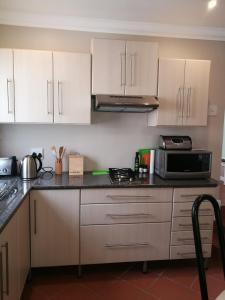 a kitchen with white cabinets and a microwave at Lucias Cottage in Cape Town