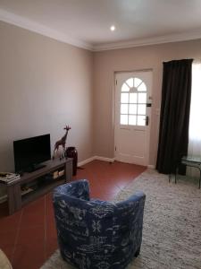 a living room with a chair and a tv at Lucias Cottage in Cape Town