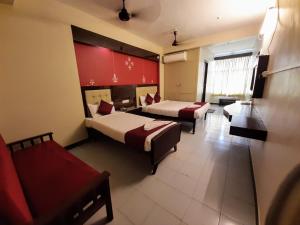a hotel room with two beds and a couch at Ravi Krishna Inn in Puducherry