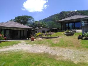 uma casa com um jardim relvado ao lado de um edifício em Eco Lodge Self-Catering em Mahé