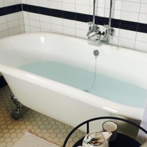 Marriner's Boutique Guesthouses في Rawene: حوض استحمام أبيض في حمام من البلاط