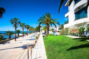 una pasarela cerca de la playa con palmeras y un edificio en Hotel Miami Mar, en Sant Carles de la Ràpita