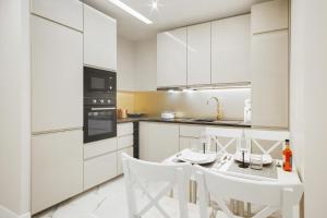 een keuken met witte kasten en een witte tafel en stoelen bij Apartments Aura Sky by Renters in Warschau