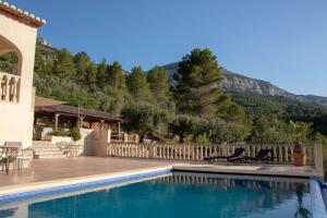 una piscina con 2 sillas junto a una casa en Villa Foia Vella - adults only, en Benichembla