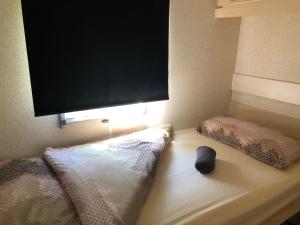 a bed with two pillows and a flat screen tv at Mobilheim am Wald in Bernau bei Berlin