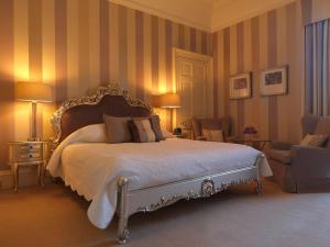 1 Schlafzimmer mit einem großen Bett und 2 Stühlen in der Unterkunft Ballathie House Hotel in Perth