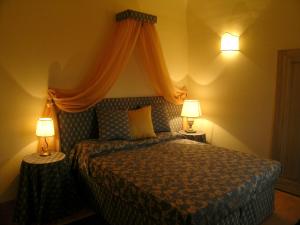 卡索萊德爾薩的住宿－Residenza Antica Canonica，一间卧室配有一张带天蓬和两盏灯的床。