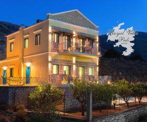 a large yellow house with a balcony at Royal Villa Pedi in Symi