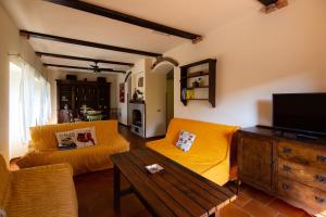 a living room with a yellow couch and a tv at Casale Il Trecento in Castiglion Fiorentino