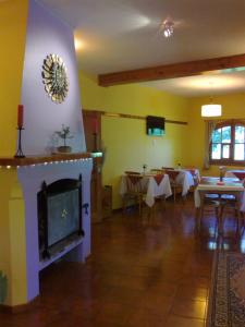 una sala de estar con chimenea y un comedor con mesas. en Posada de la Flor en San Carlos de Bariloche