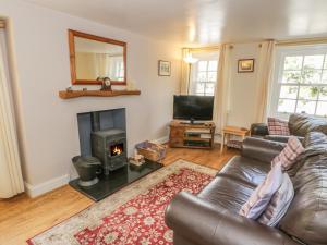 a living room with a leather couch and a fireplace at Kirk Cottage in Hownam