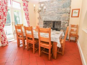een eetkamer met een tafel en stoelen en een stenen open haard bij Tyddyn Goronwy in Dyffryn