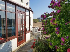 a patio with a view of the beach and flowers at The Fort in Bude