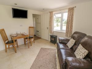 een woonkamer met een leren bank en een tafel bij Lawn Lodge in Ashleworth