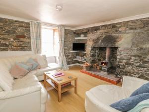 a living room with a stone wall with a fireplace at The Pink House in Isle of Whithorn