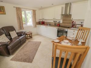 een keuken en een woonkamer met een tafel en een bank bij Lawn Lodge in Ashleworth