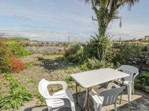 a table and chairs in a garden with the ocean at The Pink House in Isle of Whithorn