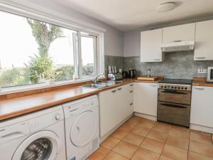 a kitchen with a washing machine and a window at The Pink House in Isle of Whithorn