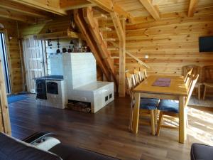 a dining room with a table and a fireplace in a log cabin at Dereniowe Wzgórze in Sejny