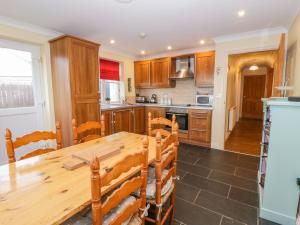 a kitchen with a wooden table and wooden cabinets at Llecyn Braf in Amlwch